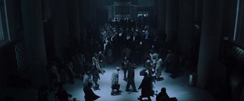 Movie still from “Unbreakable” (2000), directed by M. Night Shyamalan – A group of people walking around in a dark room; Extreme Wide shot, High angle