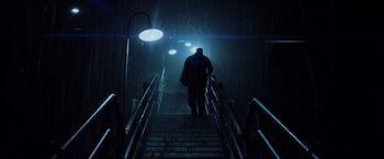 Movie still from “Unbreakable” (2000), directed by M. Night Shyamalan – A man walking up a flight of stairs in the rain; Wide shot, Low angle