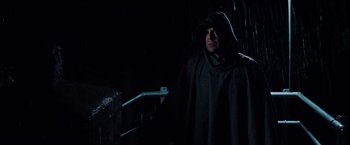 Movie still from “Unbreakable” (2000), directed by M. Night Shyamalan – A man in a hooded cloak standing in the dark; Medium shot, Over the shoulder angle