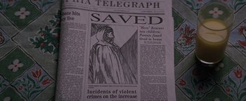 Movie still from “Unbreakable” (2000), directed by M. Night Shyamalan – A newspaper with a drawing of a person in a hooded cloak; Extreme Close Up shot, High angle
