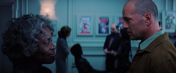 Movie still from “Unbreakable” (2000), directed by M. Night Shyamalan – A group of people standing in a room; Close Up shot, Over the shoulder angle