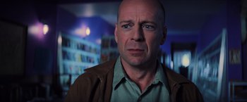 Movie still from “Unbreakable” (2000), directed by M. Night Shyamalan – A man with a bald head wearing a green shirt; Close Up shot, Over the shoulder angle