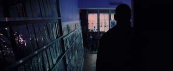 Movie still from “Unbreakable” (2000), directed by M. Night Shyamalan – A man standing in front of a book shelf in a library; Medium shot, Low angle