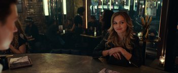 Movie still from “Uncharted” (2022), directed by Ruben Fleischer – A beautiful young lady sitting at a table; Medium shot, Over the shoulder angle