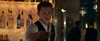 Movie still from “Uncharted” (2022), directed by Ruben Fleischer – A young man holding a cell phone in his hand; Close Up shot, Over the shoulder angle