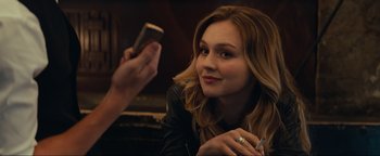 Movie still from “Uncharted” (2022), directed by Ruben Fleischer – A woman sitting in front of a cell phone; Close Up shot, Over the shoulder angle