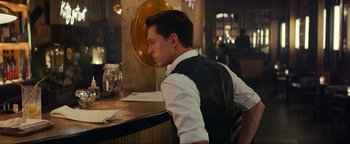 Movie still from “Uncharted” (2022), directed by Ruben Fleischer – A man sitting at a counter in front of a mirror; Medium shot, Over the shoulder angle