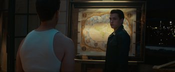 Movie still from “Uncharted” (2022), directed by Ruben Fleischer – A man standing next to another man in front of a map; Medium shot, Over the shoulder angle
