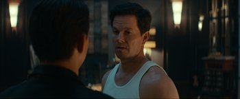 Movie still from “Uncharted” (2022), directed by Ruben Fleischer – A man in a white tank top talking to another man; Close Up shot, Over the shoulder angle