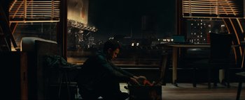 Movie still from “Uncharted” (2022), directed by Ruben Fleischer – A man sitting on the ground in front of an open box; Wide shot, High angle
