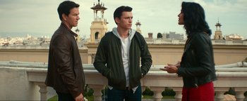 Movie still from “Uncharted” (2022), directed by Ruben Fleischer – A man standing next to two other men on a balcony; Medium shot, Over the shoulder angle