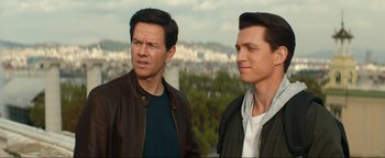 Movie still from “Uncharted” (2022), directed by Ruben Fleischer – Two men standing next to each other in front of a city; Close Up shot, Over the shoulder angle