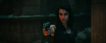 Movie still from “Uncharted” (2022), directed by Ruben Fleischer – A woman is holding a gun in a dark room; Medium shot, High angle