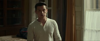 Movie still from “Uncharted” (2022), directed by Ruben Fleischer – A man in a white shirt standing in front of a window; Medium shot, Over the shoulder angle
