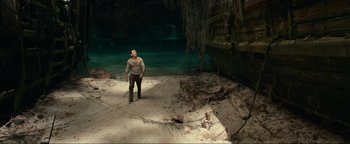 Movie still from “Uncharted” (2022), directed by Ruben Fleischer – A man standing on a beach near a body of water; Wide shot, High angle