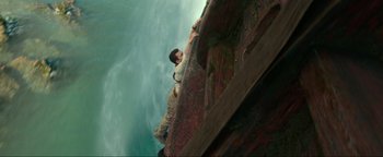 Movie still from “Uncharted” (2022), directed by Ruben Fleischer – A man sitting on top of a boat in the water; Wide shot, Overhead angle