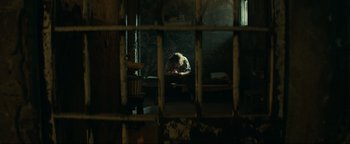 Movie still from “Uncharted” (2022), directed by Ruben Fleischer – A person sitting on a chair in a room; Wide shot, High angle