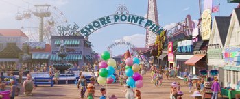 Movie still from “Under the Boardwalk” (2023), directed by David Soren – A group of people walking down a street under a sign; Extreme Wide shot, High angle