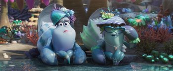 Movie still from “Under the Boardwalk” (2023), directed by David Soren – A couple of blue statues sitting next to each other on a table; Wide shot, Low angle