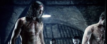 Movie still from “Underworld” (2003), directed by Len Wiseman – A man with a bloody face standing next to other men; Medium shot, Over the shoulder angle