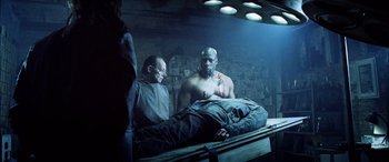 Movie still from “Underworld” (2003), directed by Len Wiseman – Two men standing next to a man lying on a bed; Medium shot, Low angle
