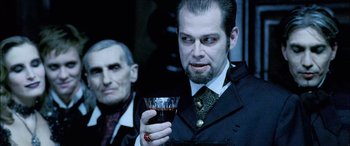 Movie still from “Underworld” (2003), directed by Len Wiseman – A man holding a wine glass in front of another man; Close Up shot, Over the shoulder angle