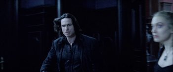 Movie still from “Underworld” (2003), directed by Len Wiseman – A man with long black hair standing in a dark room; Medium shot, Low angle