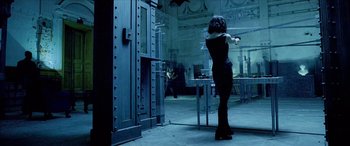 Movie still from “Underworld” (2003), directed by Len Wiseman – A woman in a black dress holding a gun in front of a mirror; Wide shot, Low angle