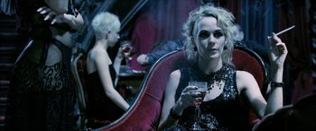 Movie still from “Underworld” (2003), directed by Len Wiseman – A woman sitting in a chair holding a glass of wine; Medium shot, Over the shoulder angle