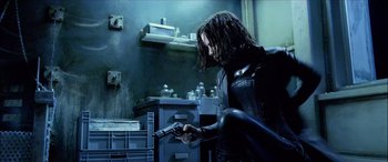 Movie still from “Underworld” (2003), directed by Len Wiseman – A man holding a gun while standing in a room; Medium shot, Low angle