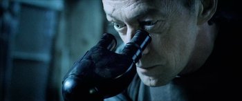 Movie still from “Underworld” (2003), directed by Len Wiseman – An older man looking through a microscope at something; Close Up shot, Over the shoulder angle