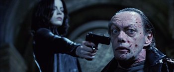 Movie still from “Underworld” (2003), directed by Len Wiseman – A woman holding a gun pointed at an older man; Close Up shot, Low angle