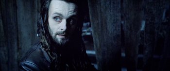 Movie still from “Underworld” (2003), directed by Len Wiseman – A man with long hair and a goatee stares at the camera; Close Up shot, Low angle
