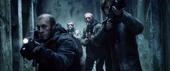 Movie still from “Underworld” (2003), directed by Len Wiseman – A group of men standing next to each other holding guns; Medium shot, Low angle