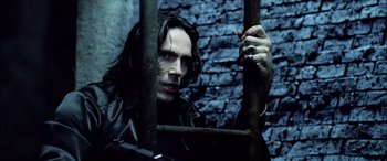 Movie still from “Underworld” (2003), directed by Len Wiseman – A man with long black hair holding onto a metal bar; Close Up shot, Low angle