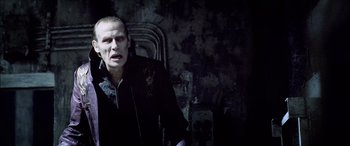 Movie still from “Underworld” (2003), directed by Len Wiseman – A man in a black jacket is standing in front of a wall; Close Up shot, Over the shoulder angle