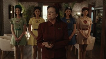 Movie still from “A League of Their Own” (2022), created by Abbi Jacobson – A group of women standing next to each other in a room; Medium shot, Low angle