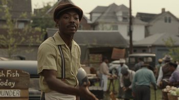 Movie still from “A League of Their Own” (2022), created by Abbi Jacobson – A man holding a plate in his hands; Medium shot, Over the shoulder angle