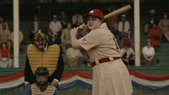 Movie still from “A League of Their Own” (2022), created by Abbi Jacobson – A man in a baseball uniform holding a baseball bat; Medium shot, Over the shoulder angle
