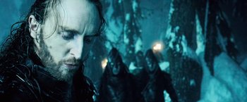 Movie still from “Underworld: Evolution” (2006), directed by Len Wiseman – A group of people in the snow with a man in the background; Close Up shot, Low angle