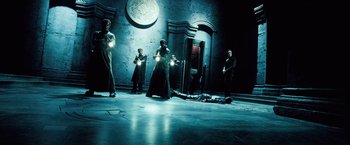 Movie still from “Underworld: Evolution” (2006), directed by Len Wiseman – A group of people standing in a dark room; Wide shot, High angle