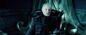 Movie still from “Underworld: Evolution” (2006), directed by Len Wiseman – An older man sitting in a chair in a dark room; Close Up shot, Over the shoulder angle