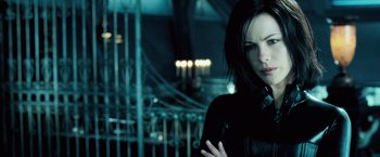 Movie still from “Underworld: Evolution” (2006), directed by Len Wiseman – A woman standing in front of a metal fence; Close Up shot, Over the shoulder angle