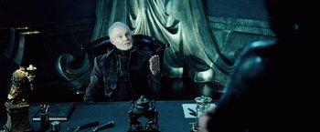 Movie still from “Underworld: Evolution” (2006), directed by Len Wiseman – An older man sitting in front of a mirror in a room; Medium shot, Over the shoulder angle
