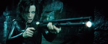 Movie still from “Underworld: Evolution” (2006), directed by Len Wiseman – A woman is holding a gun and aiming it at the camera; Close Up shot, Low angle