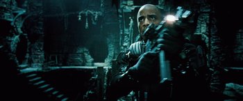 Movie still from “Underworld: Evolution” (2006), directed by Len Wiseman – A man holding a gun while standing next to a wall; Medium shot, Low angle