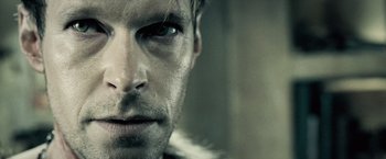 Movie still from “Underworld: Evolution” (2006), directed by Len Wiseman – A man's face in a dark room; Extreme Close Up shot, Over the shoulder angle