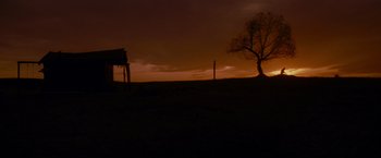 Movie still from “Unforgiven” (1992), directed by Clint Eastwood – A tree is silhouetted against a dark sky at sunset; Extreme Wide shot, Low angle