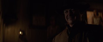 Movie still from “Unforgiven” (1992), directed by Clint Eastwood – A man wearing a cowboy hat in the dark; Close Up shot, Over the shoulder angle