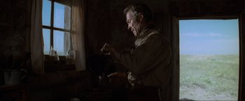Movie still from “Unforgiven” (1992), directed by Clint Eastwood – An older man is pouring something from a pot into a cup; Medium shot, Low angle